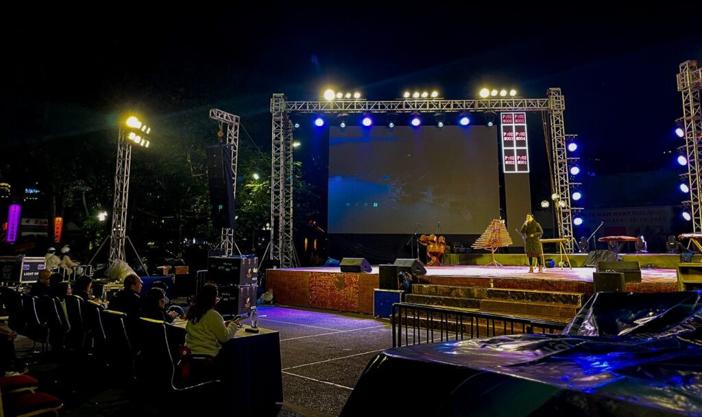 Outdoor stage setup with screen and audience at night